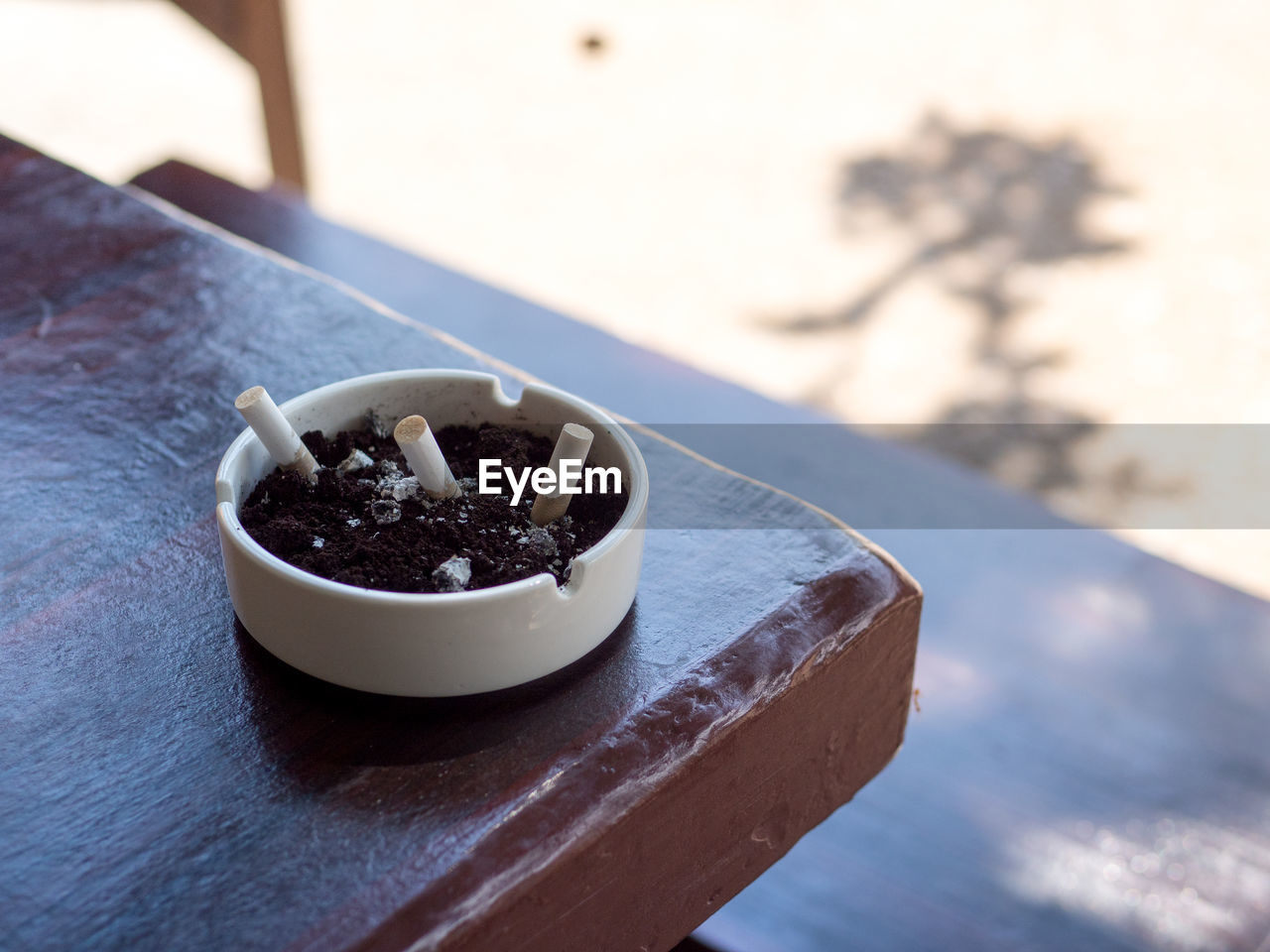 CLOSE-UP HIGH ANGLE VIEW OF CIGARETTE IN CONTAINER ON TABLE