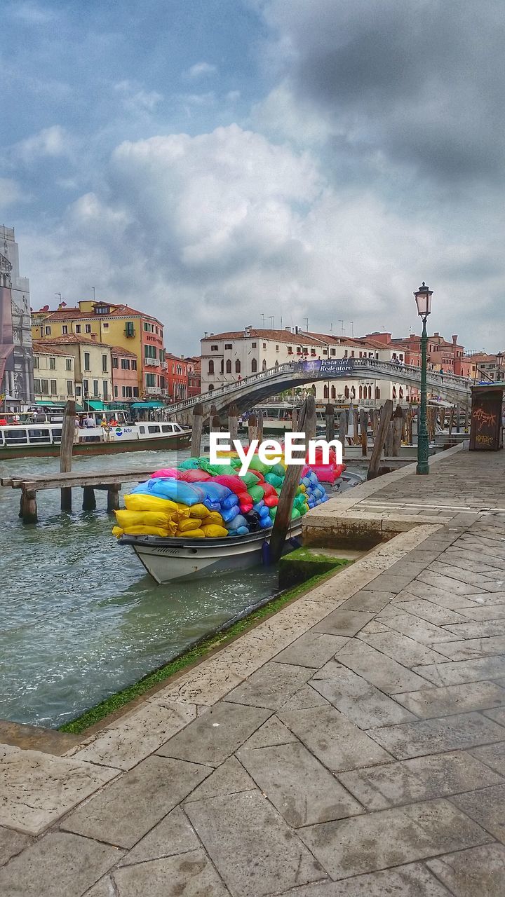 GRAFFITI ON RIVER BY BUILDINGS AGAINST SKY