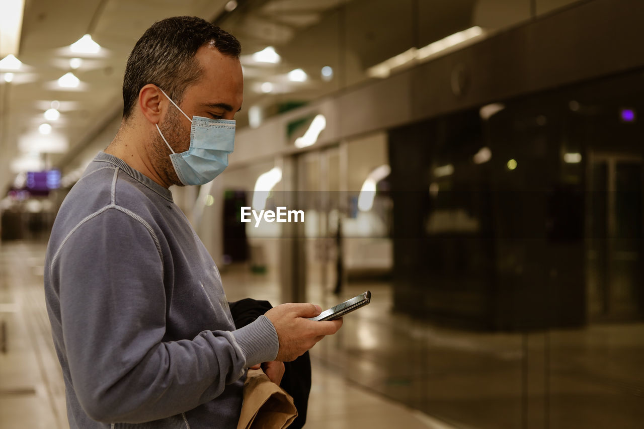 Side view of man using mobile phone while standing in city