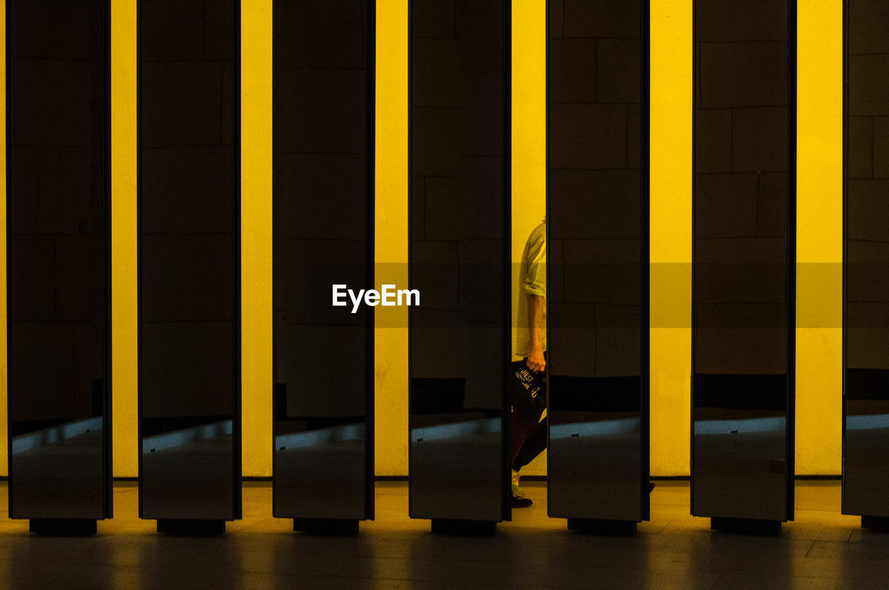 Row of illuminated yellow columns with a fleeting silhouette in one of them.