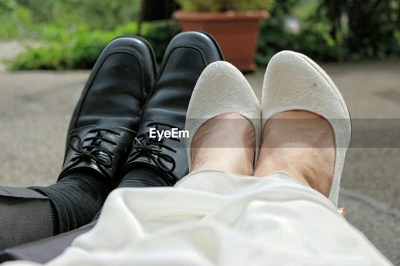 Low section of couple sitting at park during wedding ceremony