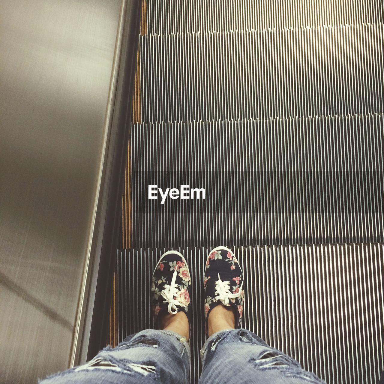 Low section of woman standing on escalator