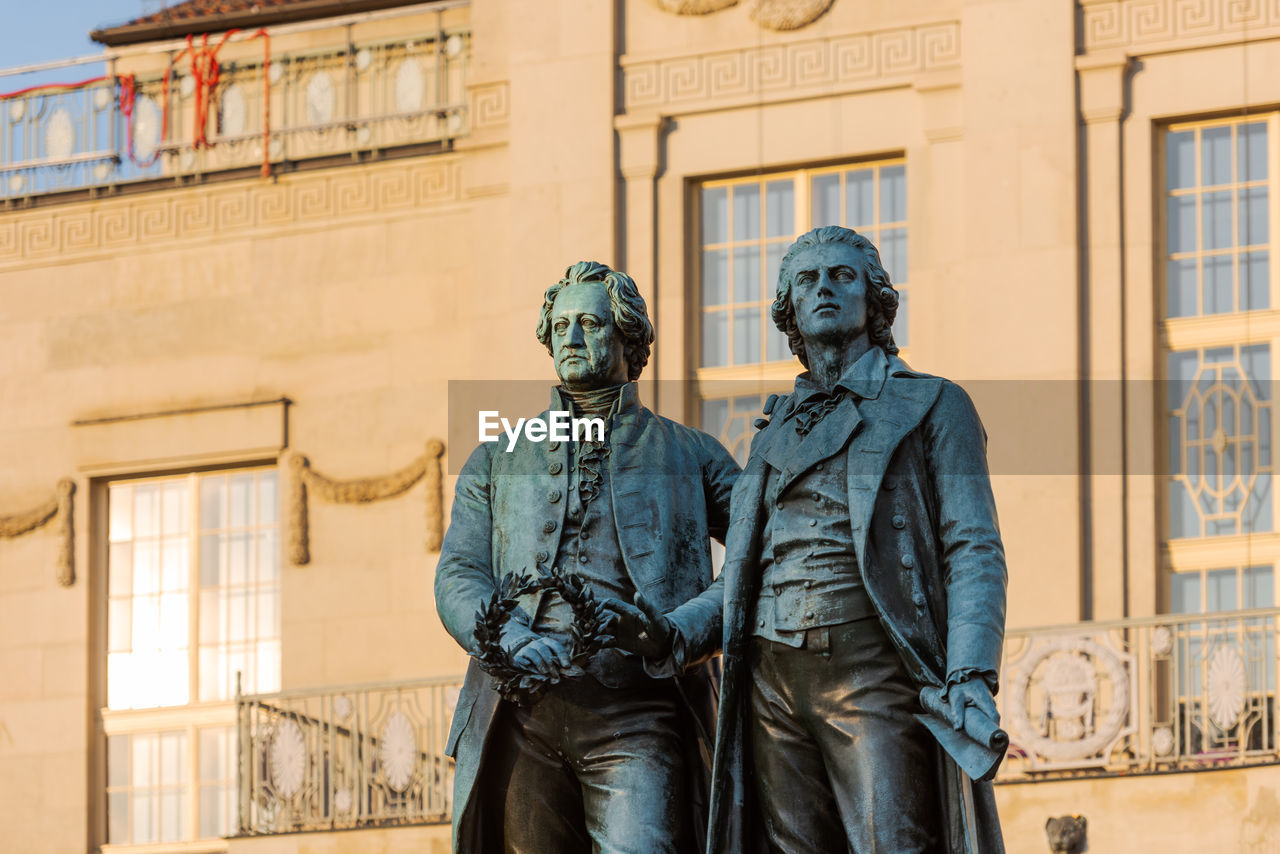 Statue of man standing against building