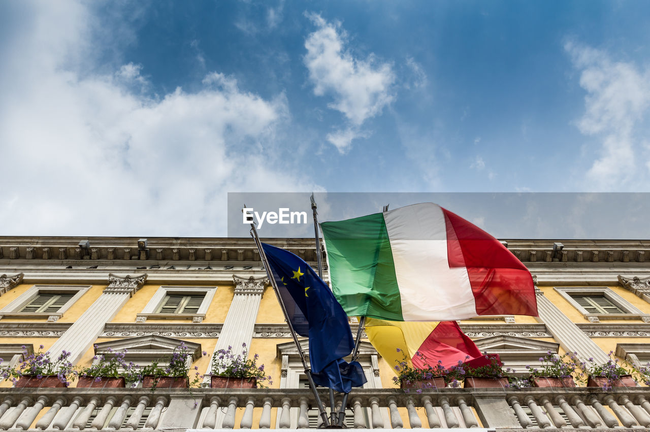 Low angle view of flags on building against sky