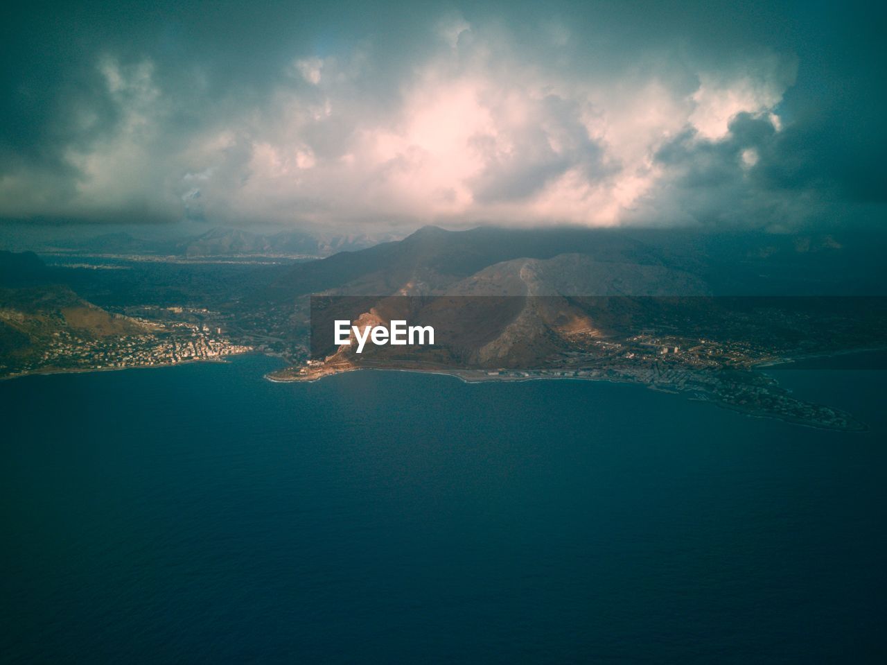 AERIAL VIEW OF SEA BY MOUNTAINS AGAINST SKY