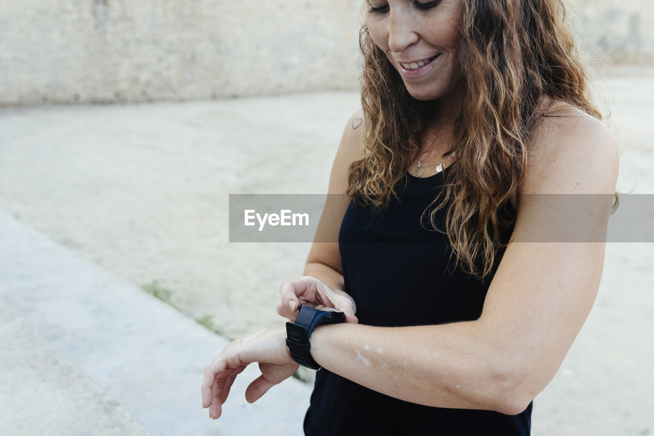 Young woman setting her watch before practicing urban crossfit.