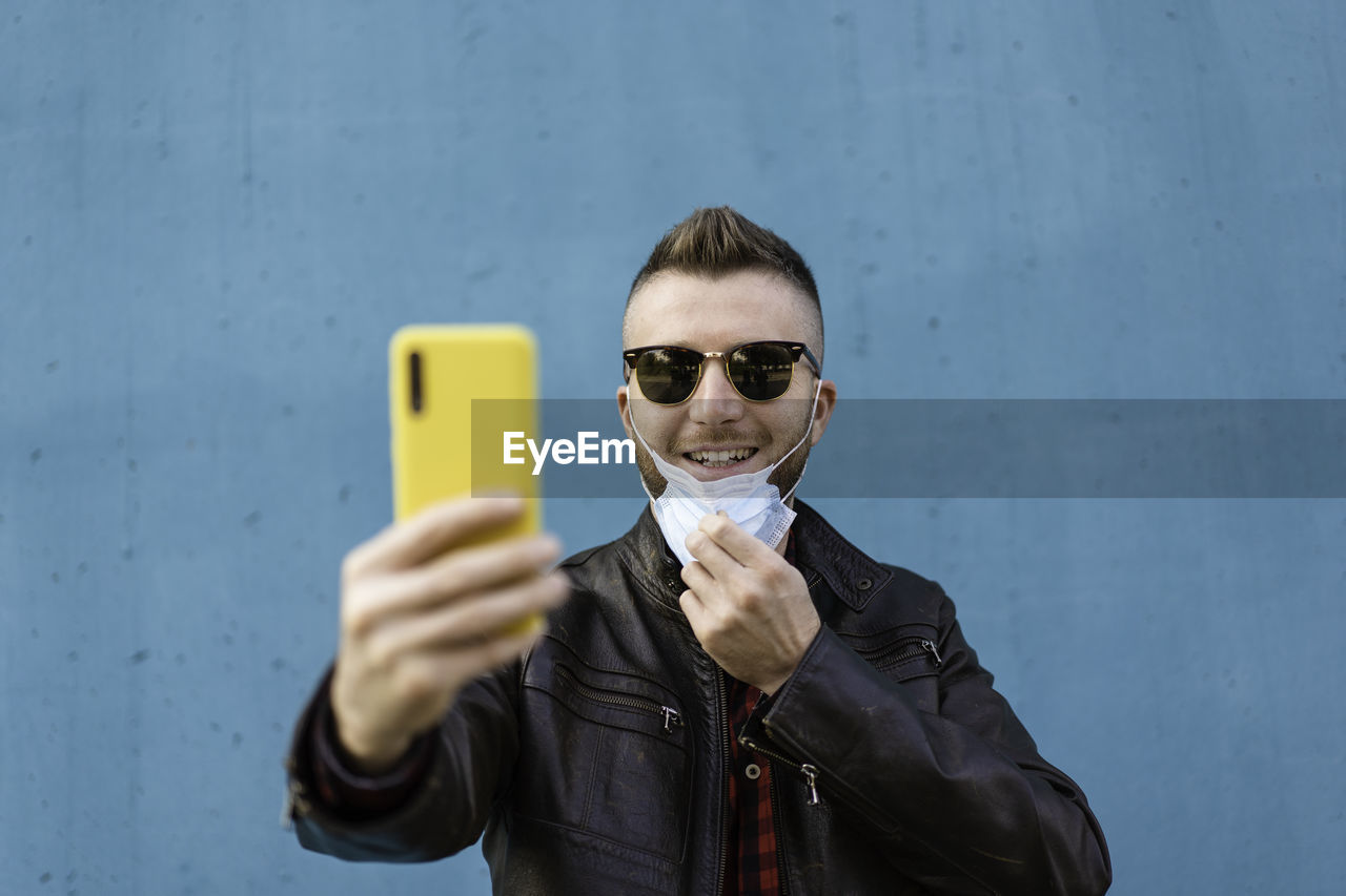 PORTRAIT OF YOUNG MAN USING PHONE