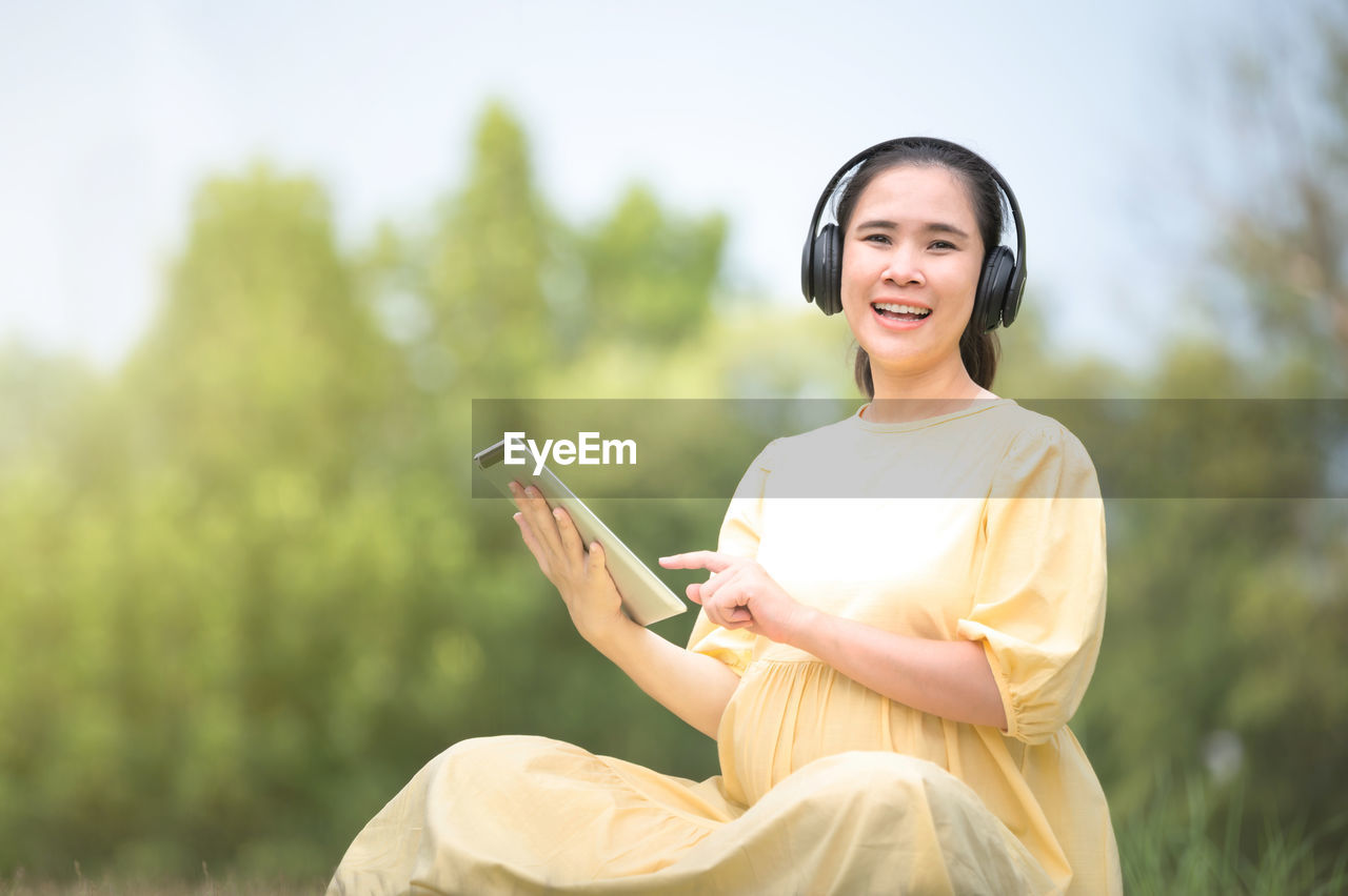 YOUNG WOMAN USING MOBILE PHONE WHILE SITTING ON CAMERA AT SMART