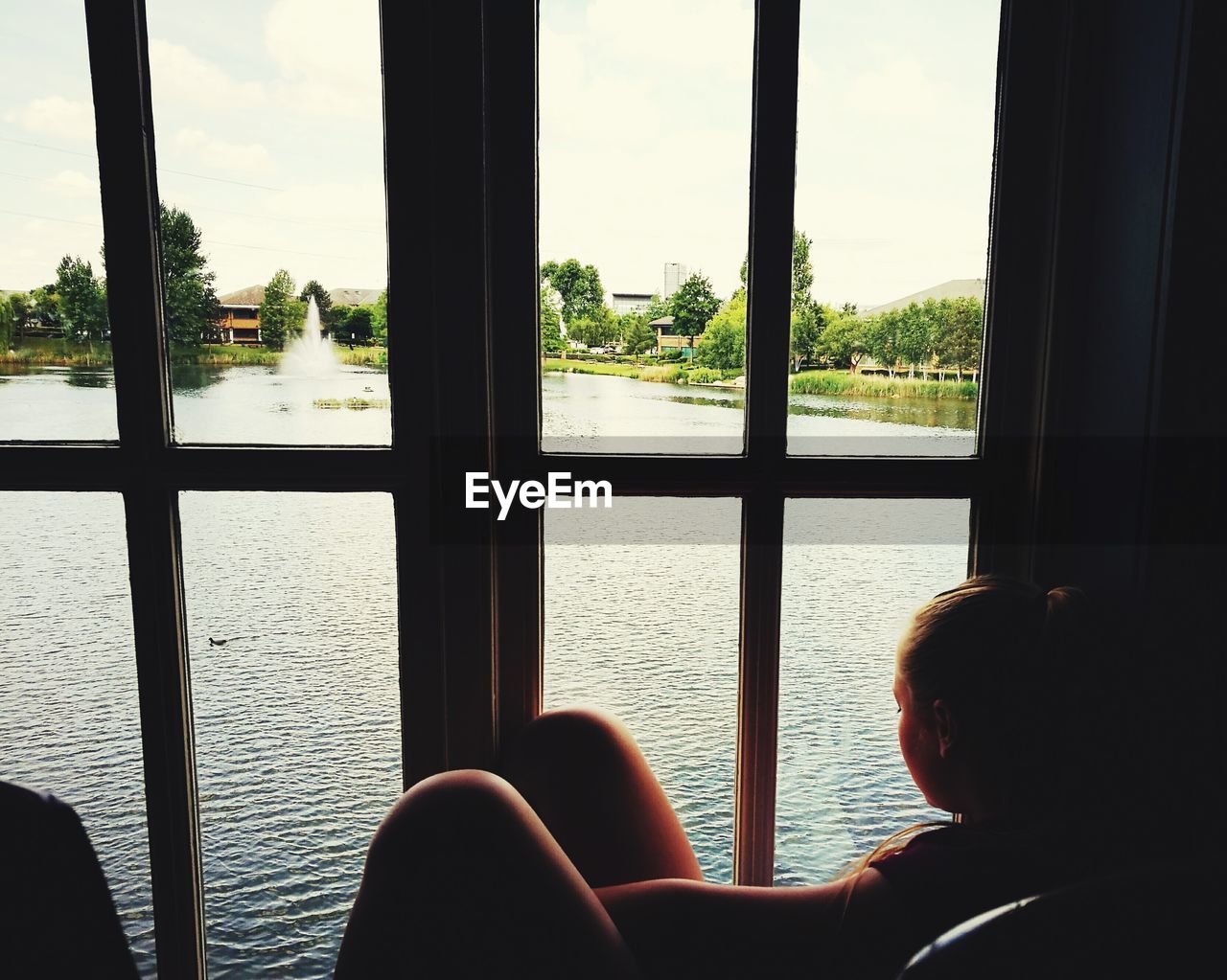 Woman looking at lake through window