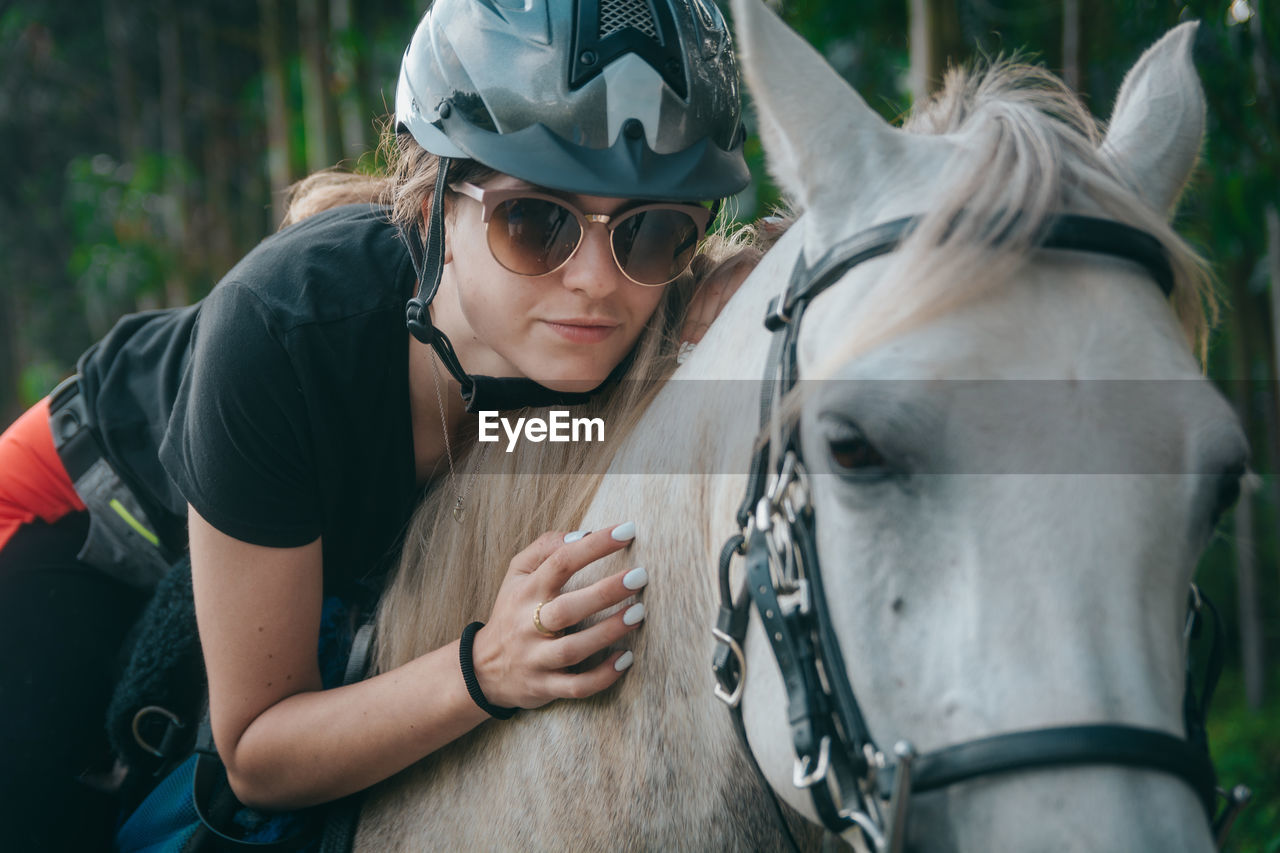 Woman wearing sunglasses and helmet riding horse 