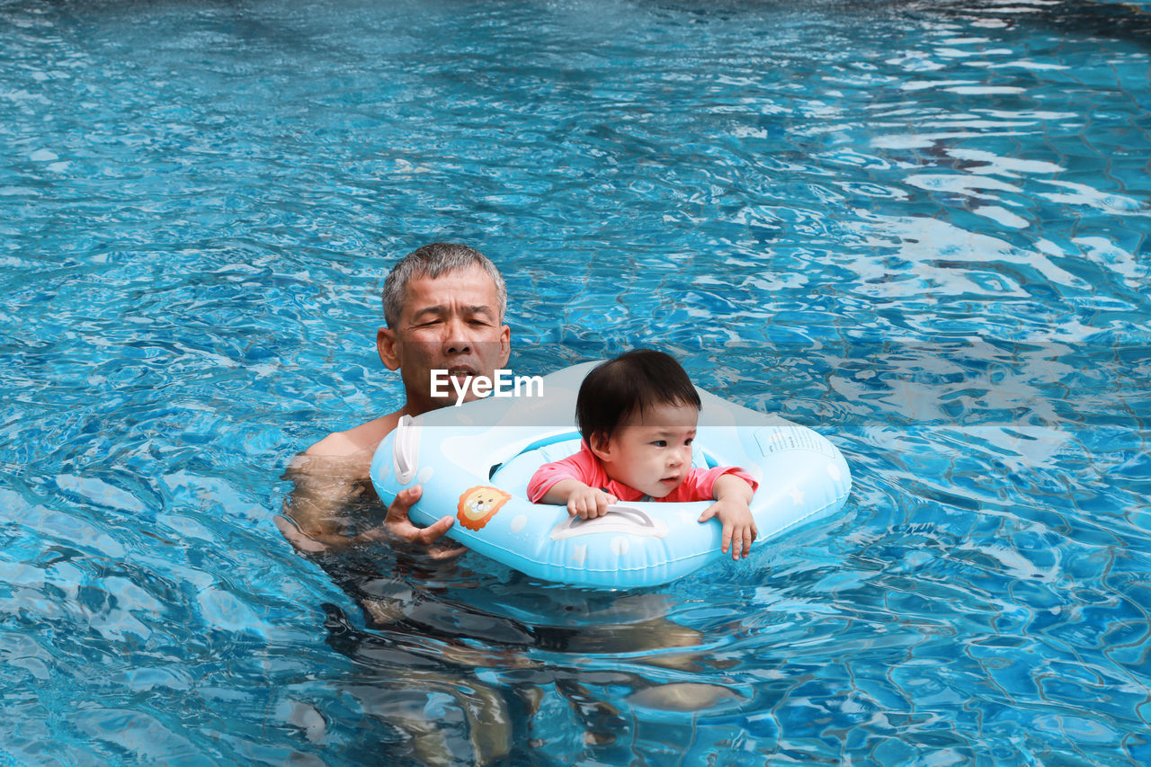 High angle view of father and daughter swimming in pool