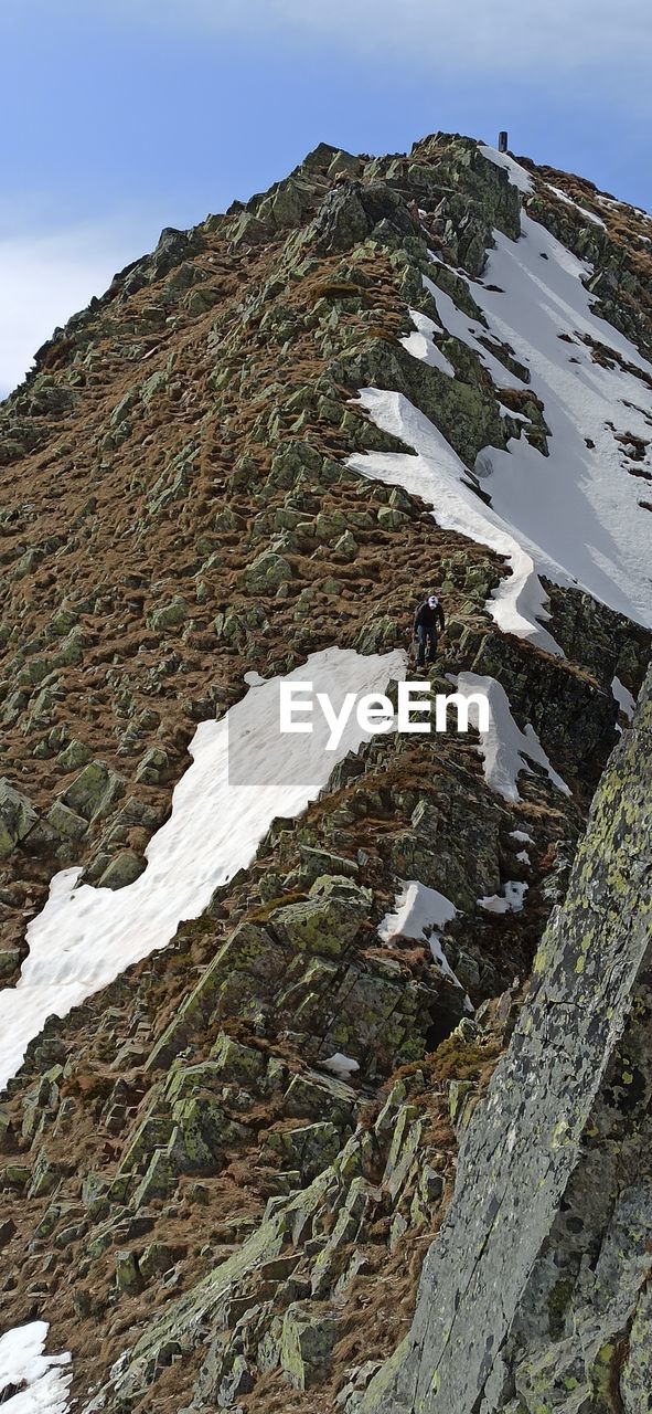 SNOW COVERED ROCK ON MOUNTAIN AGAINST SKY