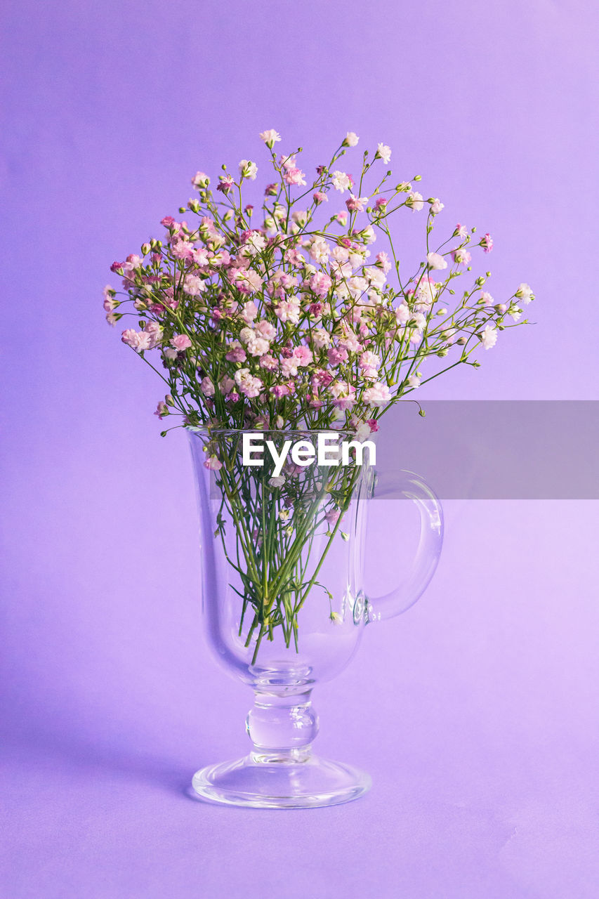 CLOSE-UP OF FRESH FLOWER VASE ON TABLE AGAINST WALL