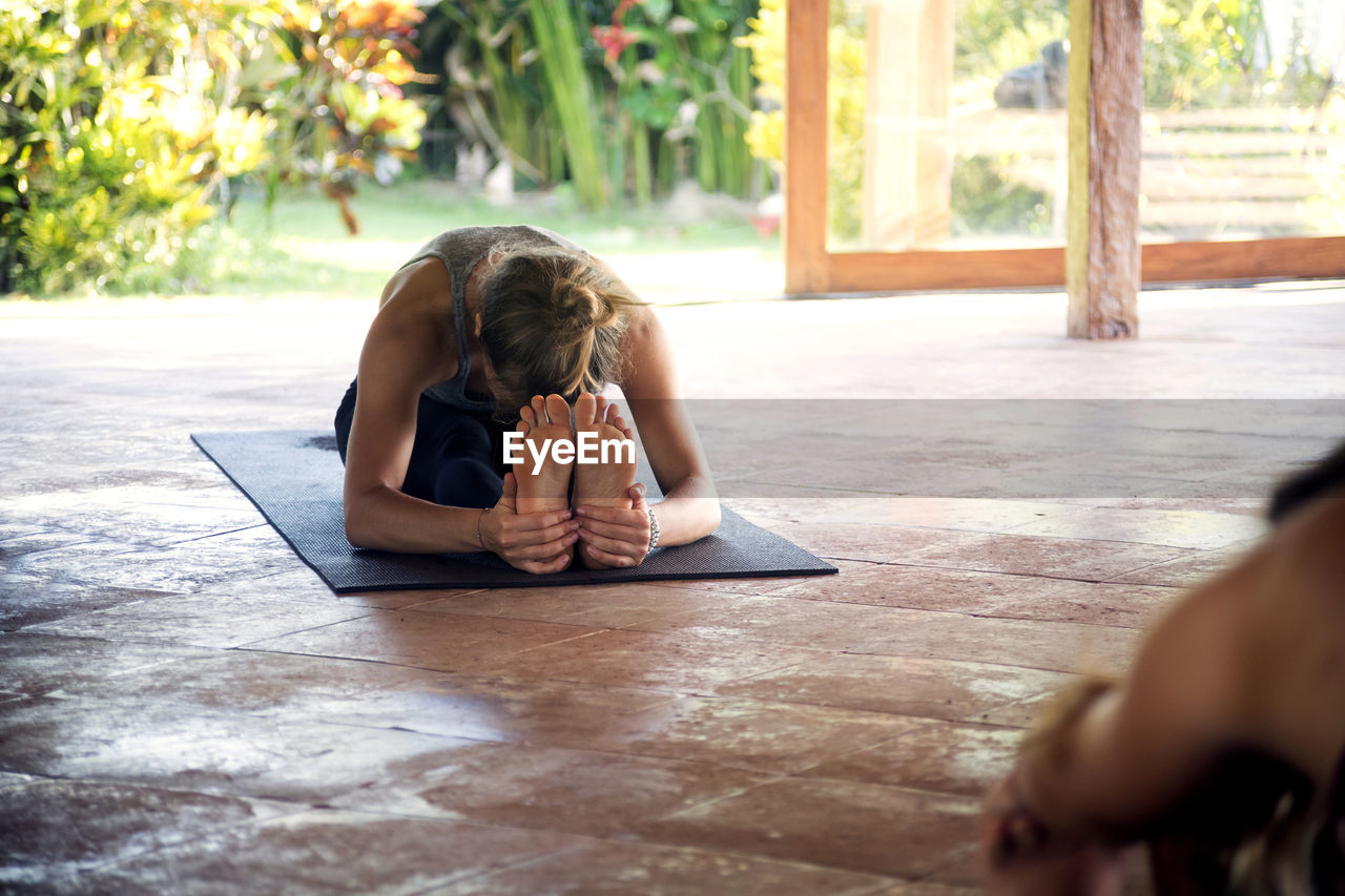 Woman practicing seated forward bend pose in yoga studio