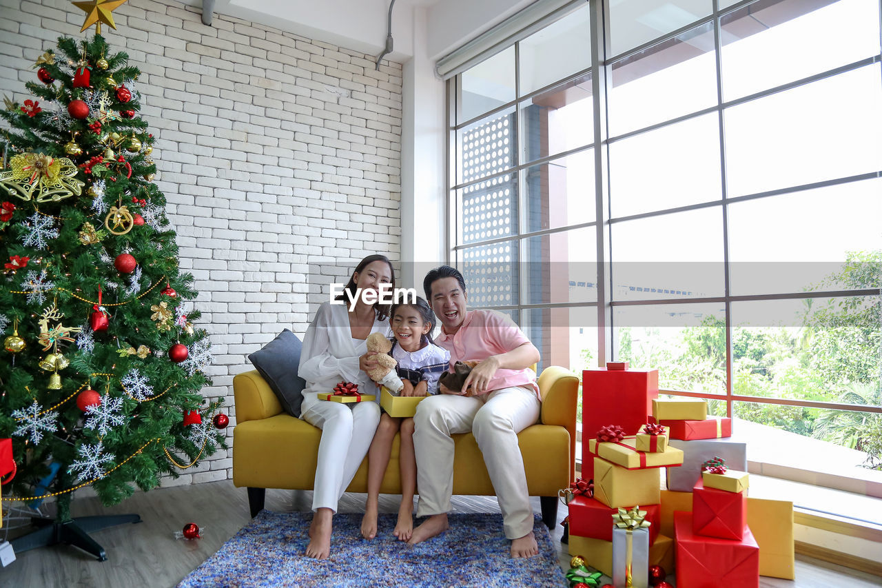 Cheerful family with christmas gift while sitting at home