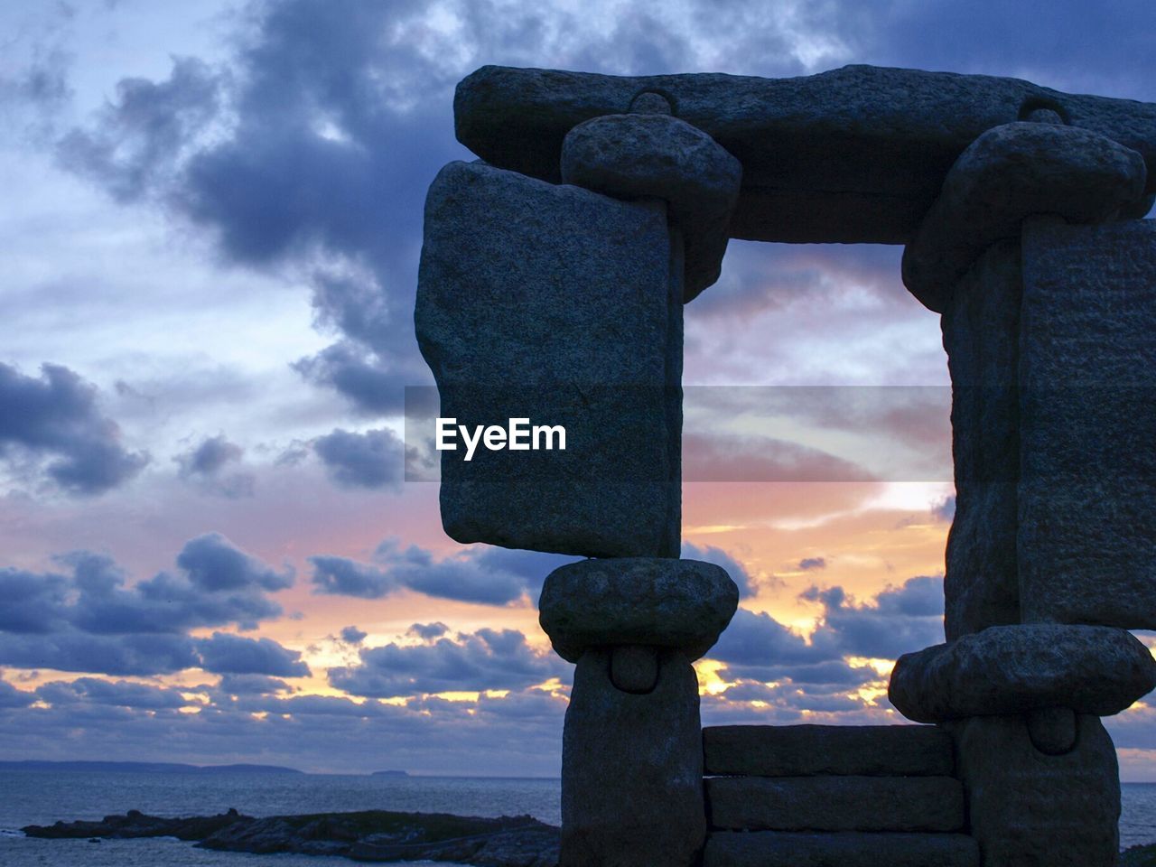 LOW ANGLE VIEW OF STATUE AGAINST SUNSET SKY