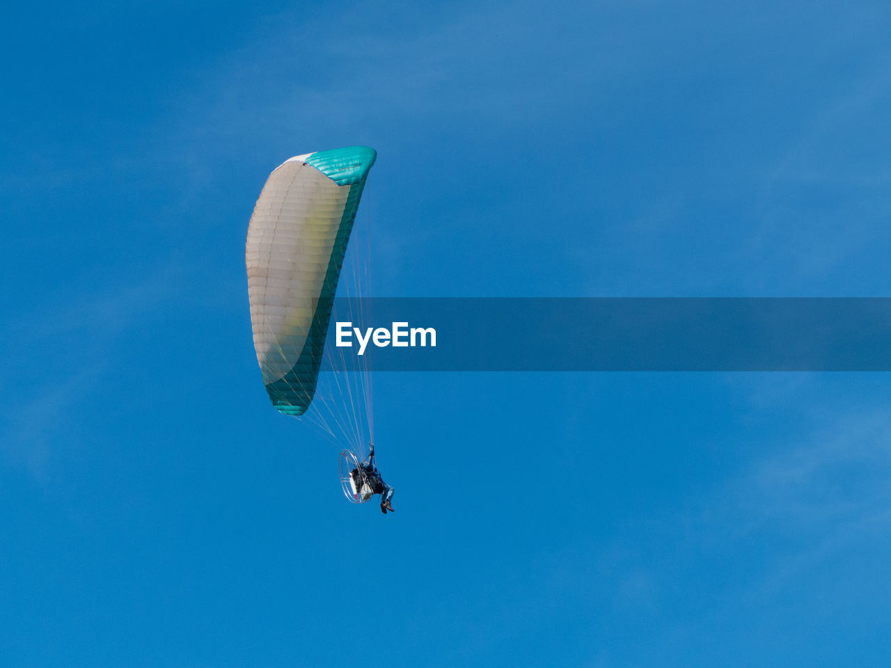 Low angle view of person paragliding against blue sky