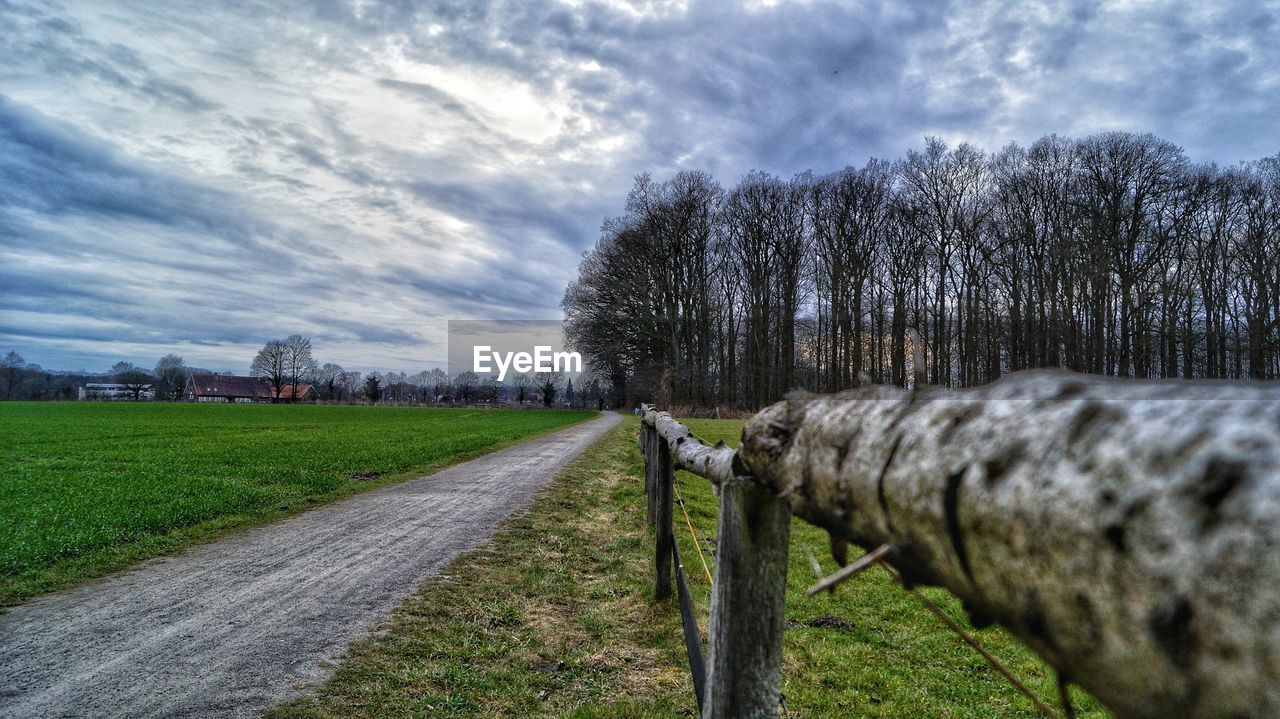 Empty road amidst field against sky