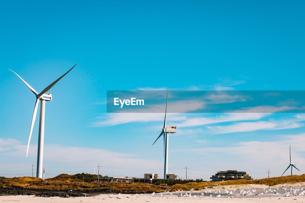 Wind turbines on field against sky