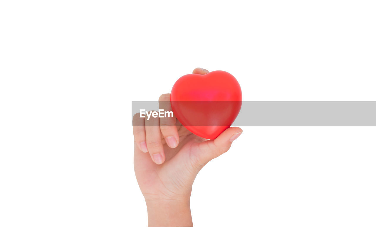 MIDSECTION OF PERSON HOLDING HEART SHAPE AGAINST WHITE BACKGROUND