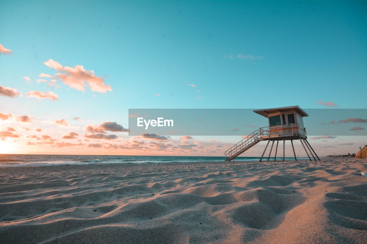 View of lifeguard hut on beach against sky during sunset