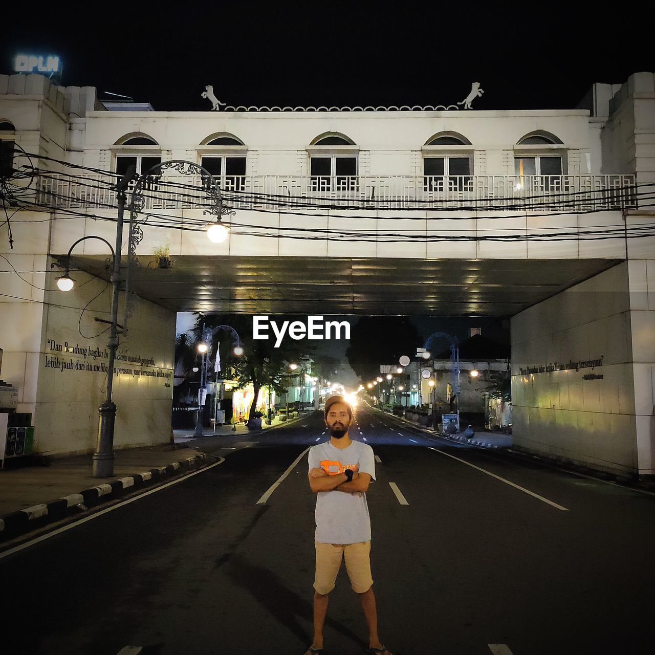 WOMAN STANDING ON ILLUMINATED BRIDGE AT NIGHT