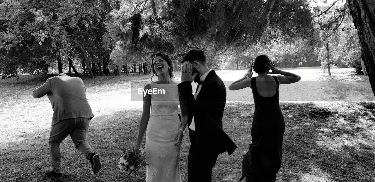 Bride and bridegroom standing with friends on field