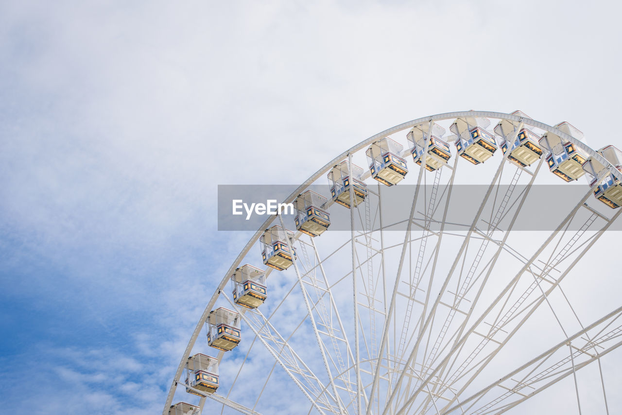 Low angle view of ferris wheel against cloudy sky