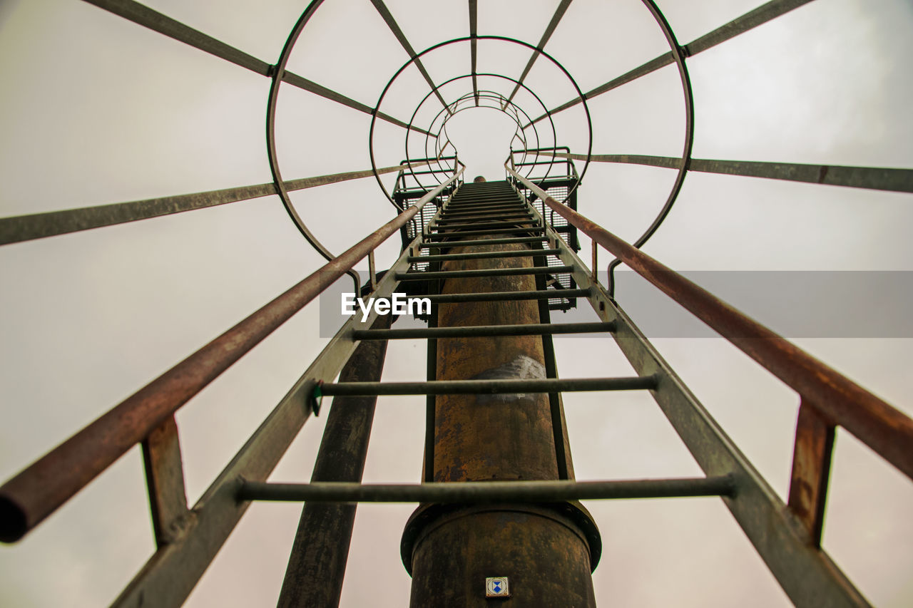 Low angle view of metallic ladder against sky