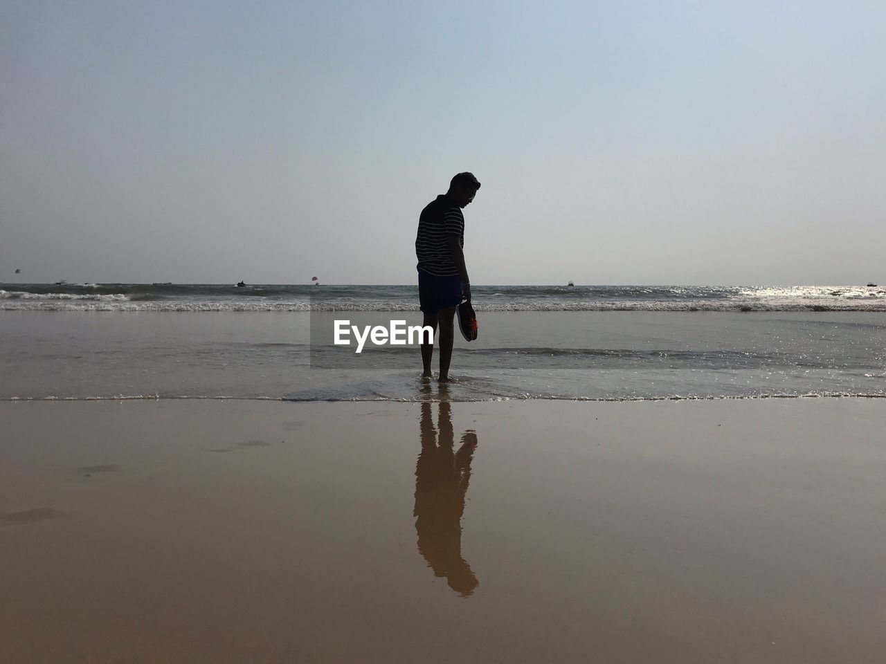 REAR VIEW OF SILHOUETTE MAN STANDING ON BEACH