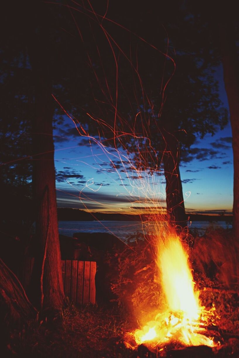 Close-up of campfire against the sea at sunset