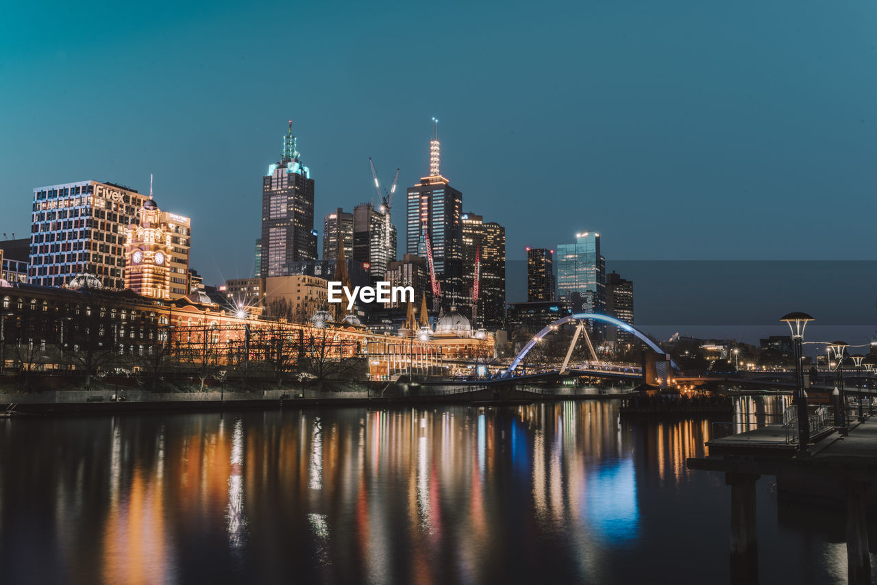 Reflection of illuminated buildings on river in city at night