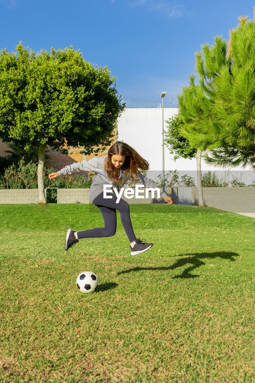 Full length of girl playing soccer ball on grass