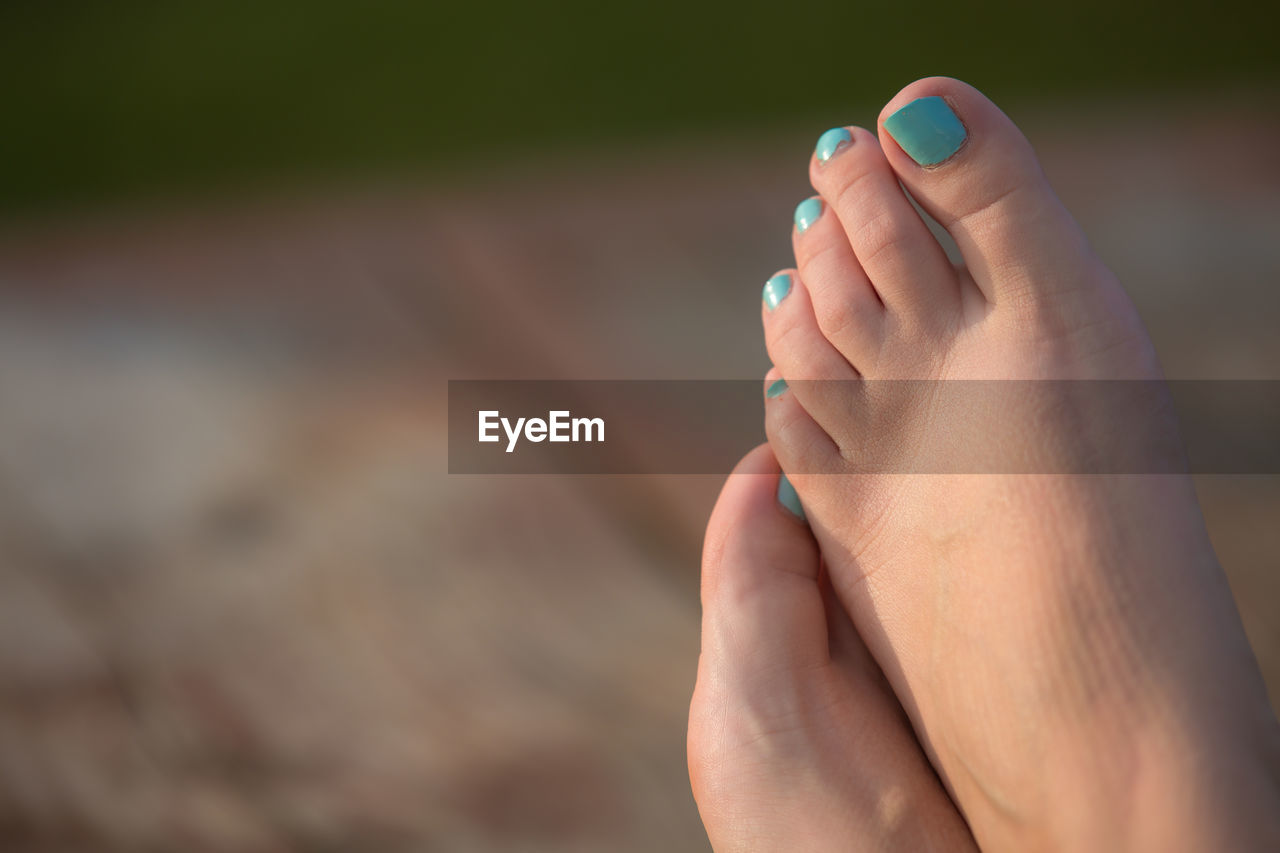 Low section of woman with bare feet wearing blue nail polish