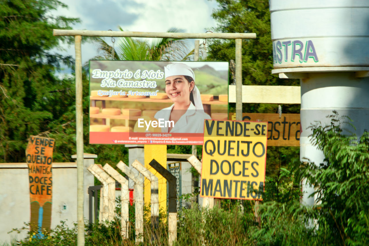 PORTRAIT OF A SMILING WOMAN WITH TEXT AGAINST PLANTS