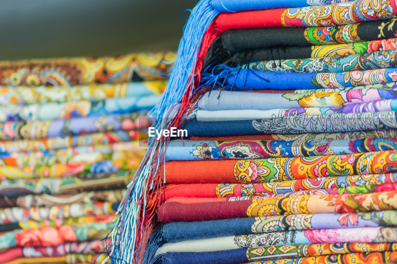 Stack of multi colored shawls for sale at market stall