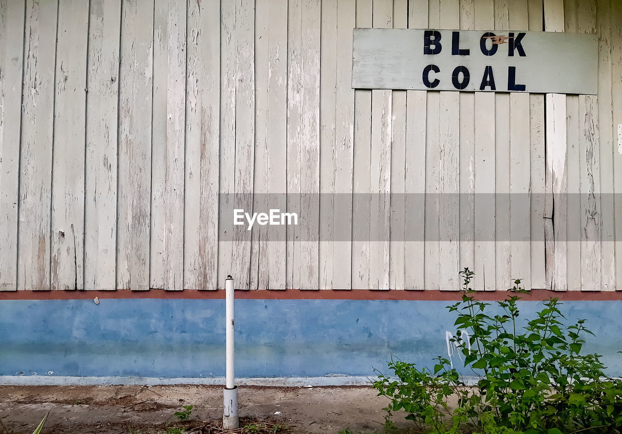 wall, text, architecture, communication, western script, built structure, sign, no people, wood, day, wall - building feature, building exterior, entrance, outdoors, number, door, nature, closed, urban area, plant, house, information sign, facade, security