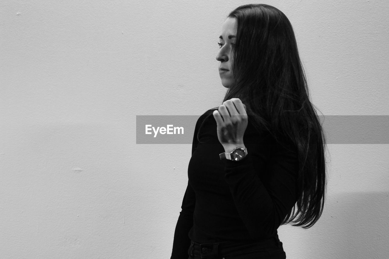 Woman with long hair standing against wall