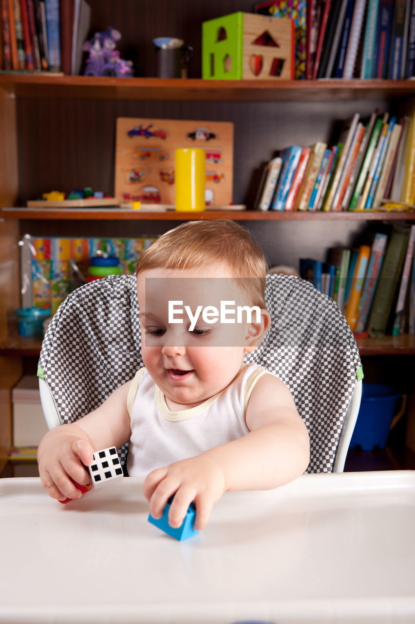 Cute baby boy playing with toy blocks on table