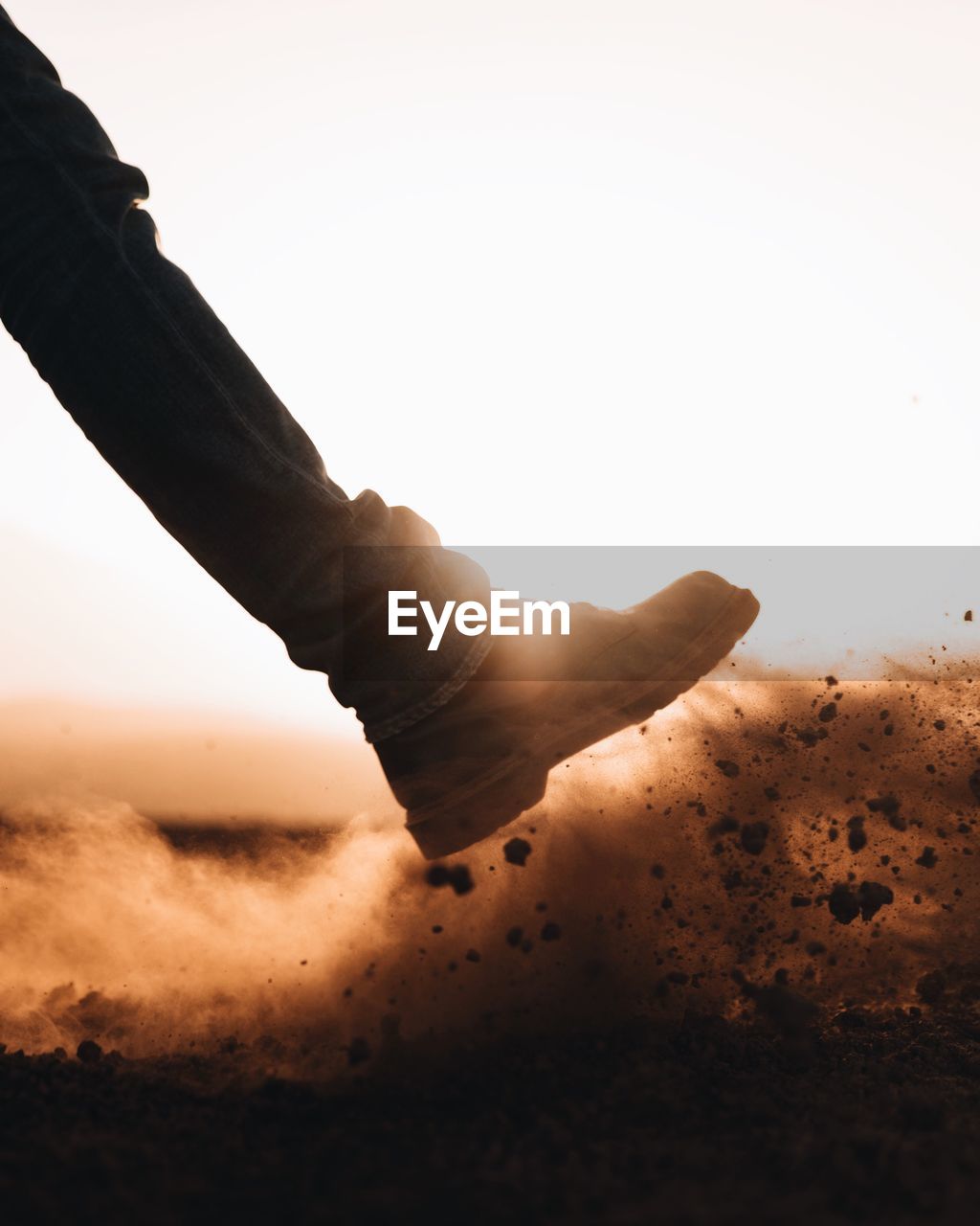 Low section of person on sand against clear sky