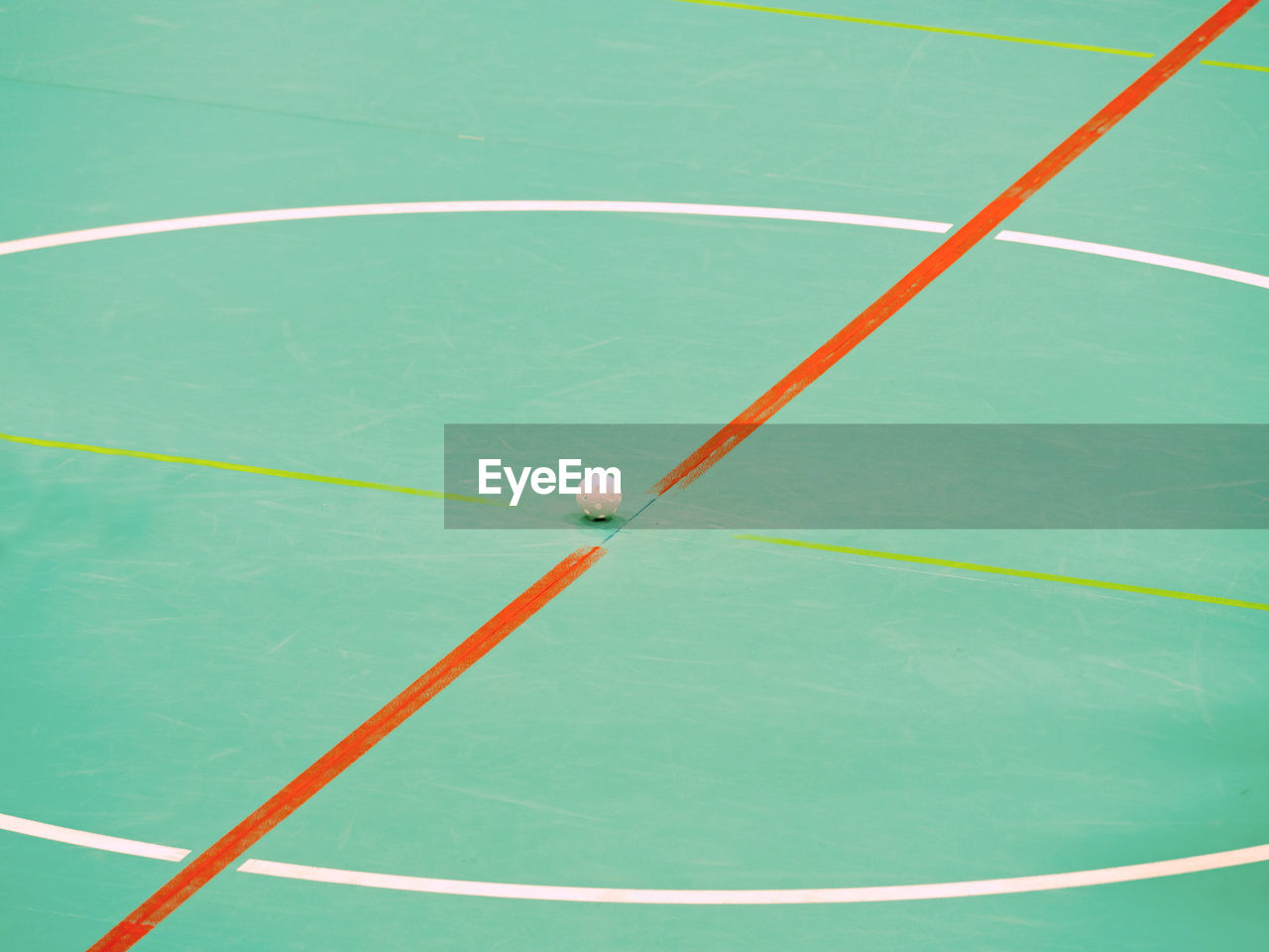 Bully of floor-ball court. white ball in middle on floor of sports hall with colorful marking lines.