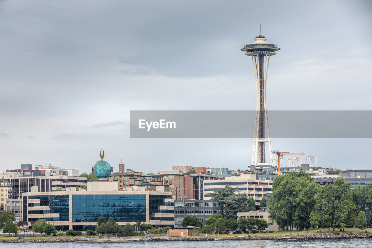 Communications tower in city against sky