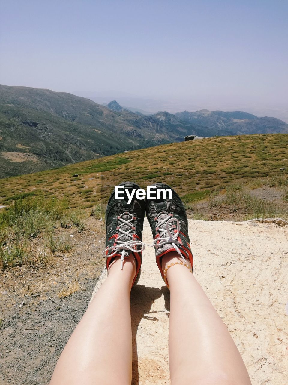 Low section of woman on mountain against sky