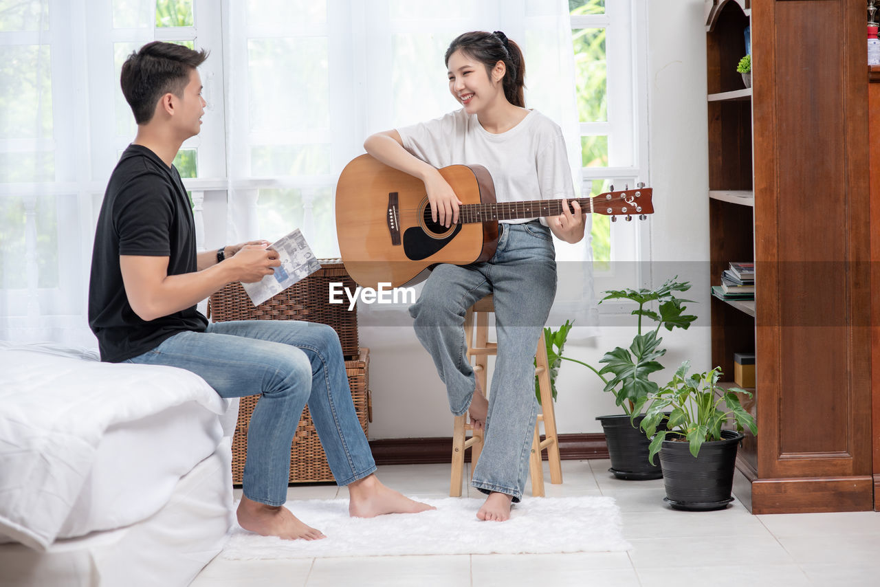 YOUNG COUPLE PLAYING GUITAR AT MUSIC