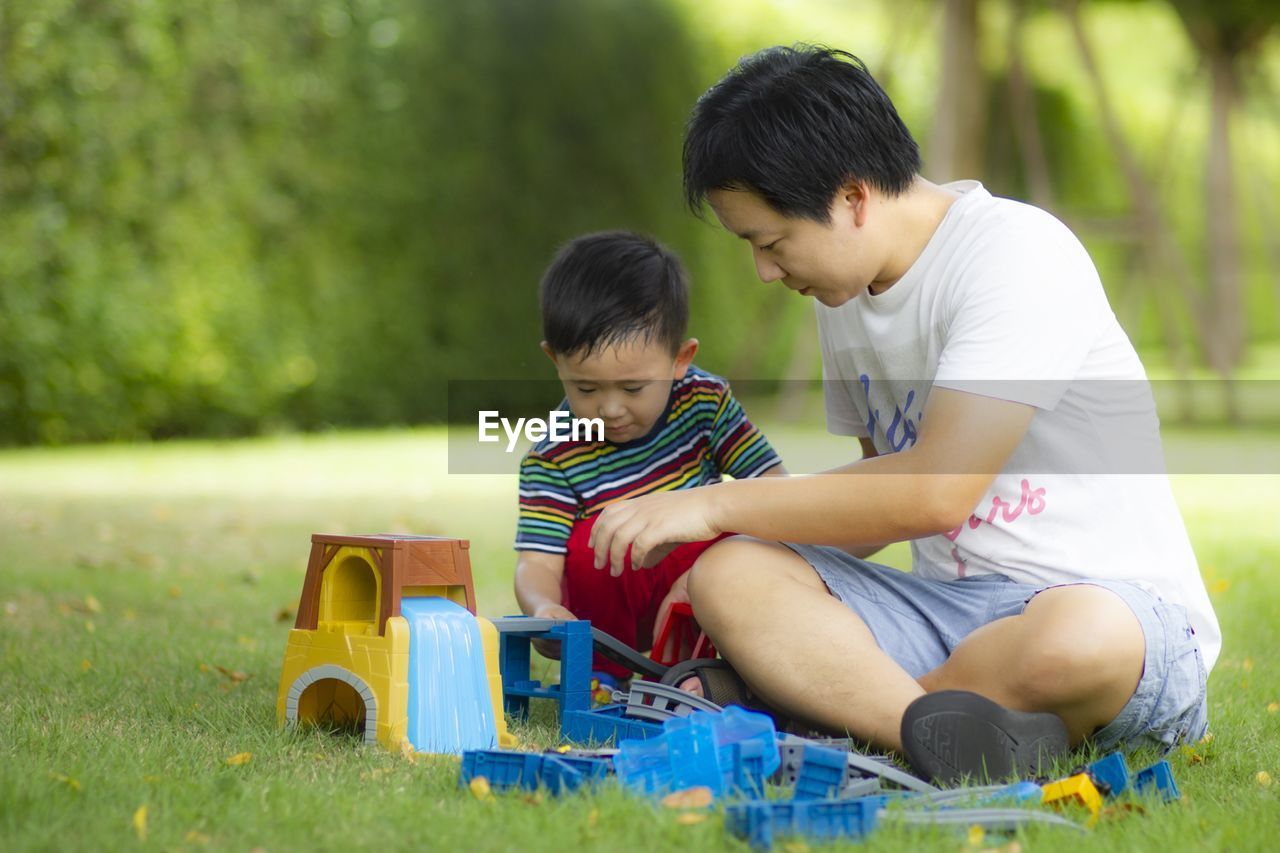 Father and son playing with toys on grass