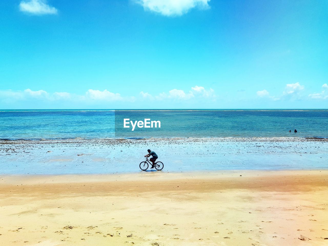 MAN RIDING BICYCLE ON BEACH