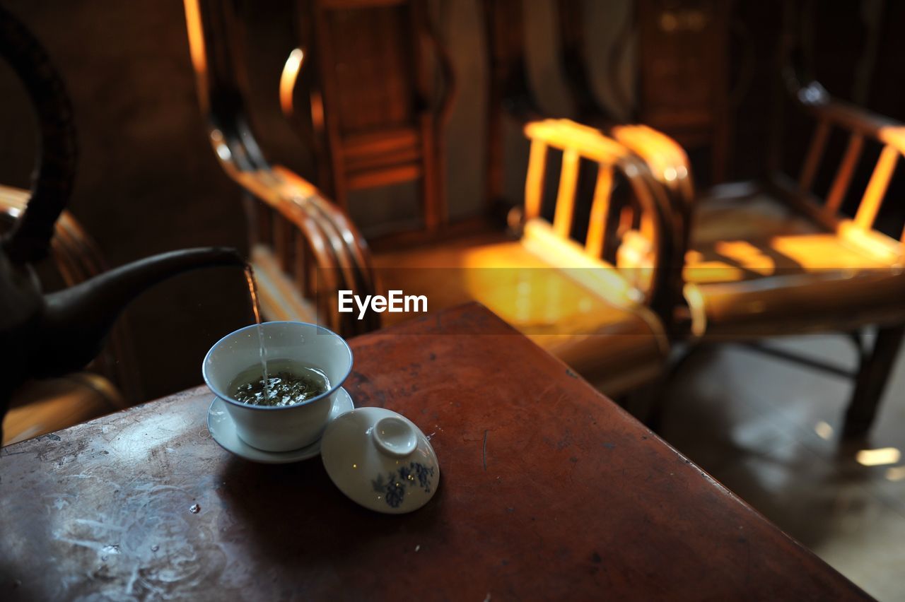 Cropped pot pouring tea in cup on table