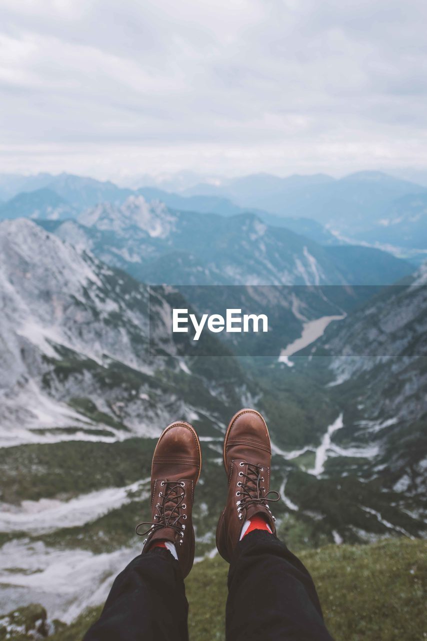 Low section of man on mountain against sky