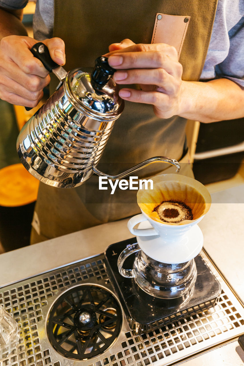 Midsection of barista preparing coffee in cafe