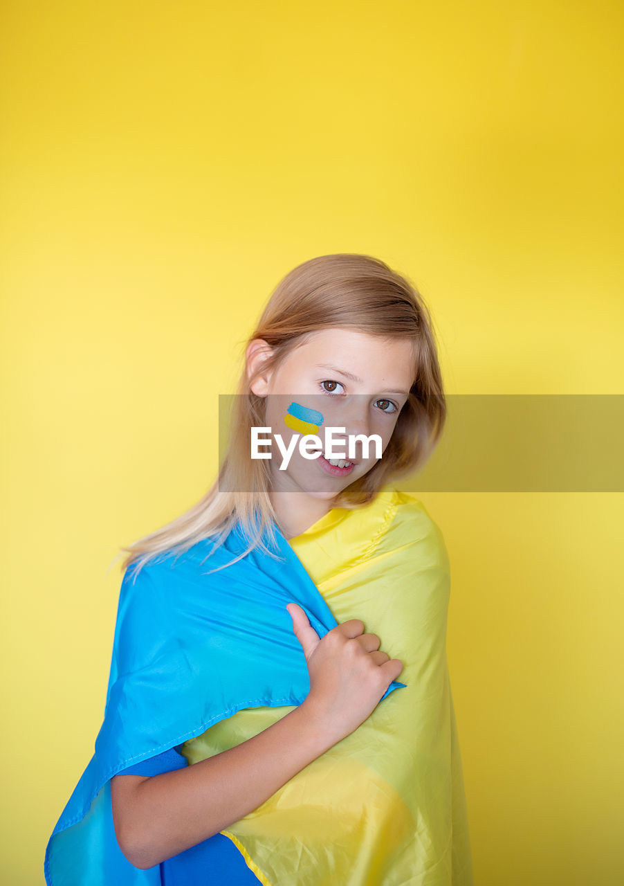 Portrait of young woman against yellow background